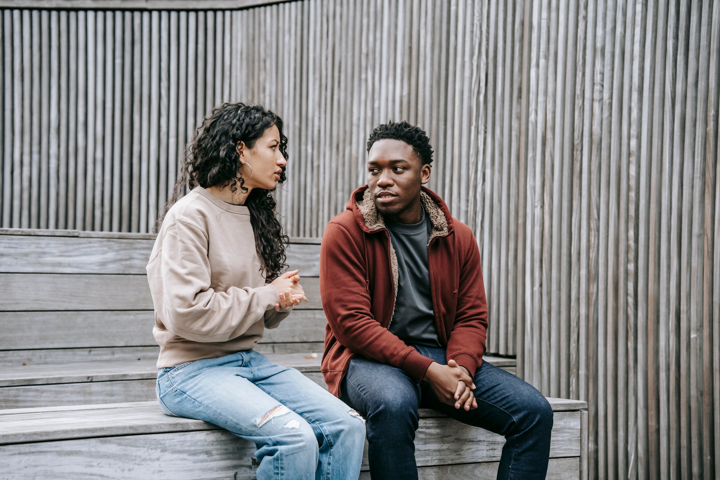 Unsatisfied multiethnic couple having conversation on stairs