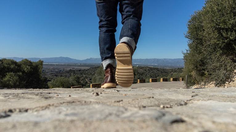 Feet of man walking on mountain road