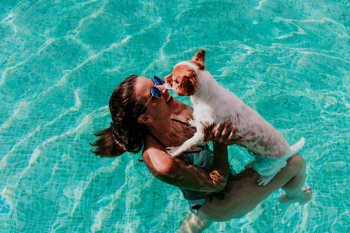 Happy Young Woman and Dog in a Pool Having Fun