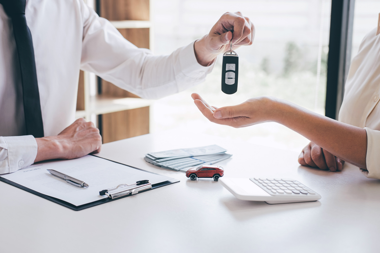 Car rent agent manager holding key of new car giving to woman client after signing good deal agreement contract, renting considering vehicle