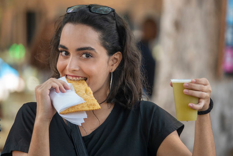 Girl eating a pastel and drinking sugarcane juice